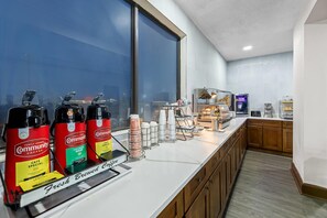 Un comptoir de café avec des distributeurs de café, une machine à café et une vue sur la rue.