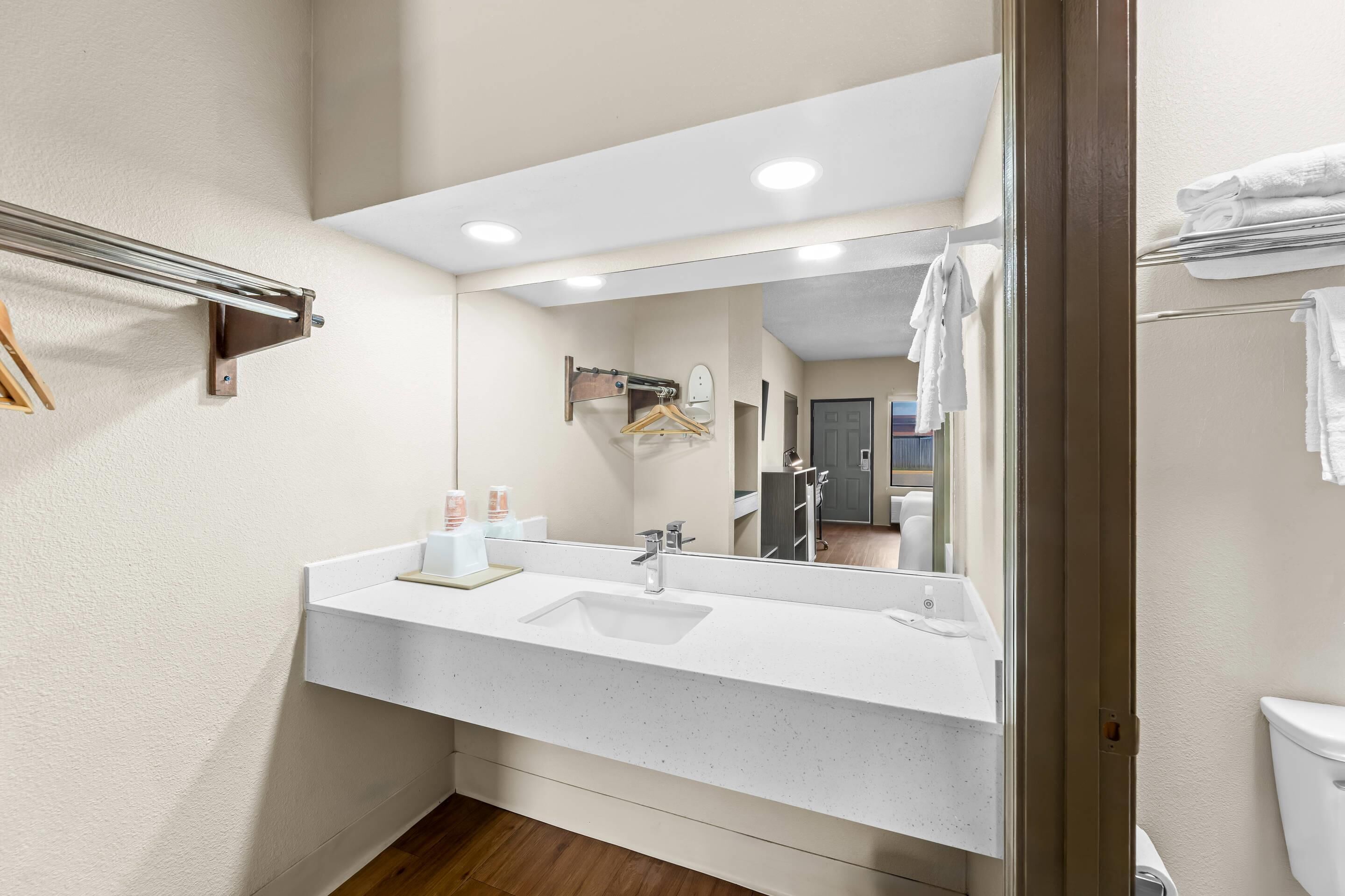 Une salle de bain avec un lavabo blanc, un miroir et un porte-serviettes.
