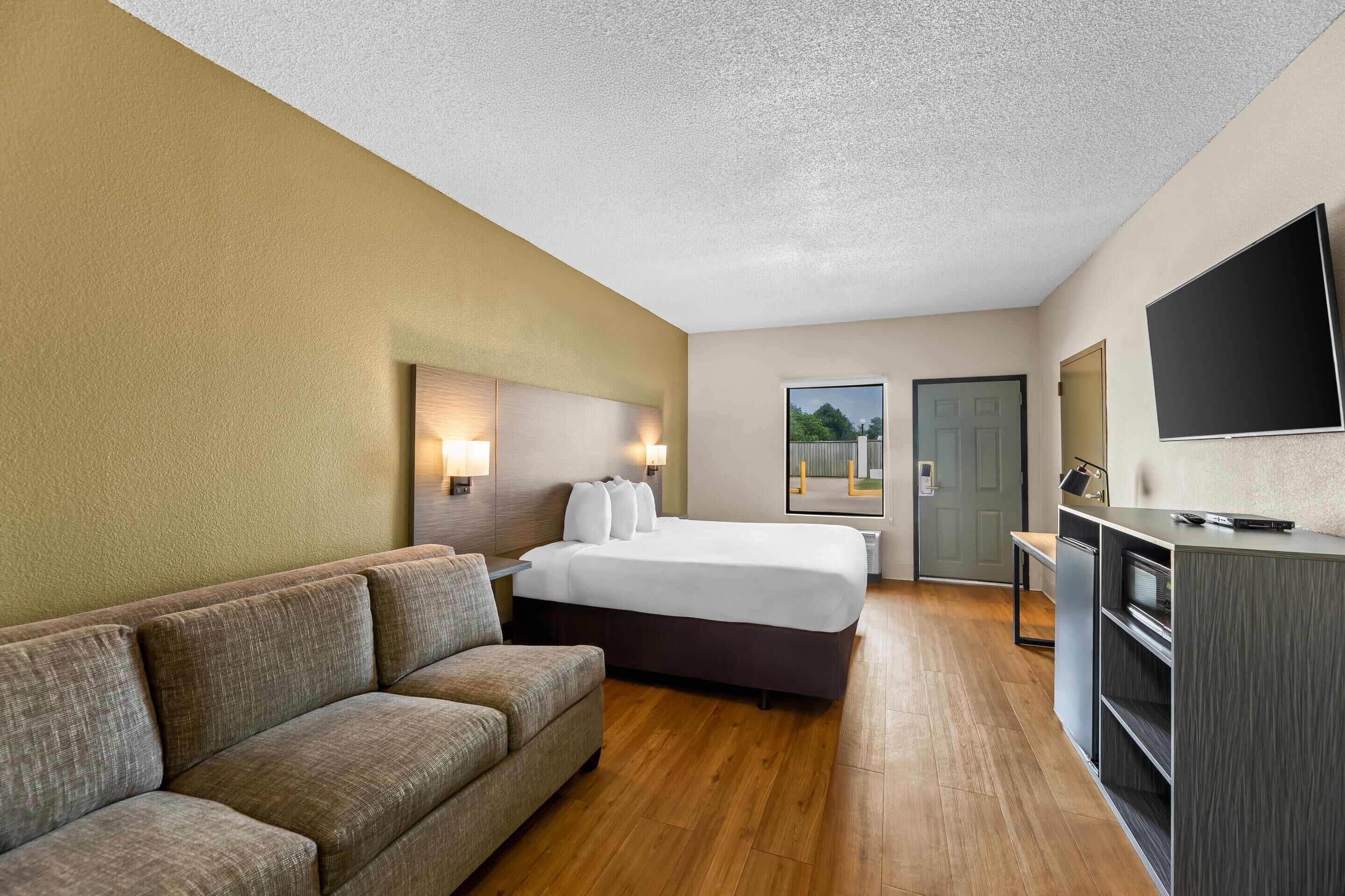 Een hotelkamer met een bed, een bank, een bureau en een televisie.