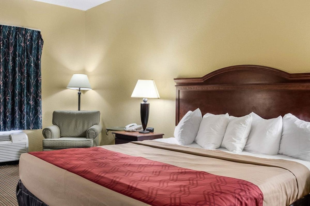 Ett hotellrum med en säng, två sänglampor, en stol, ett skrivbord och en telefon.