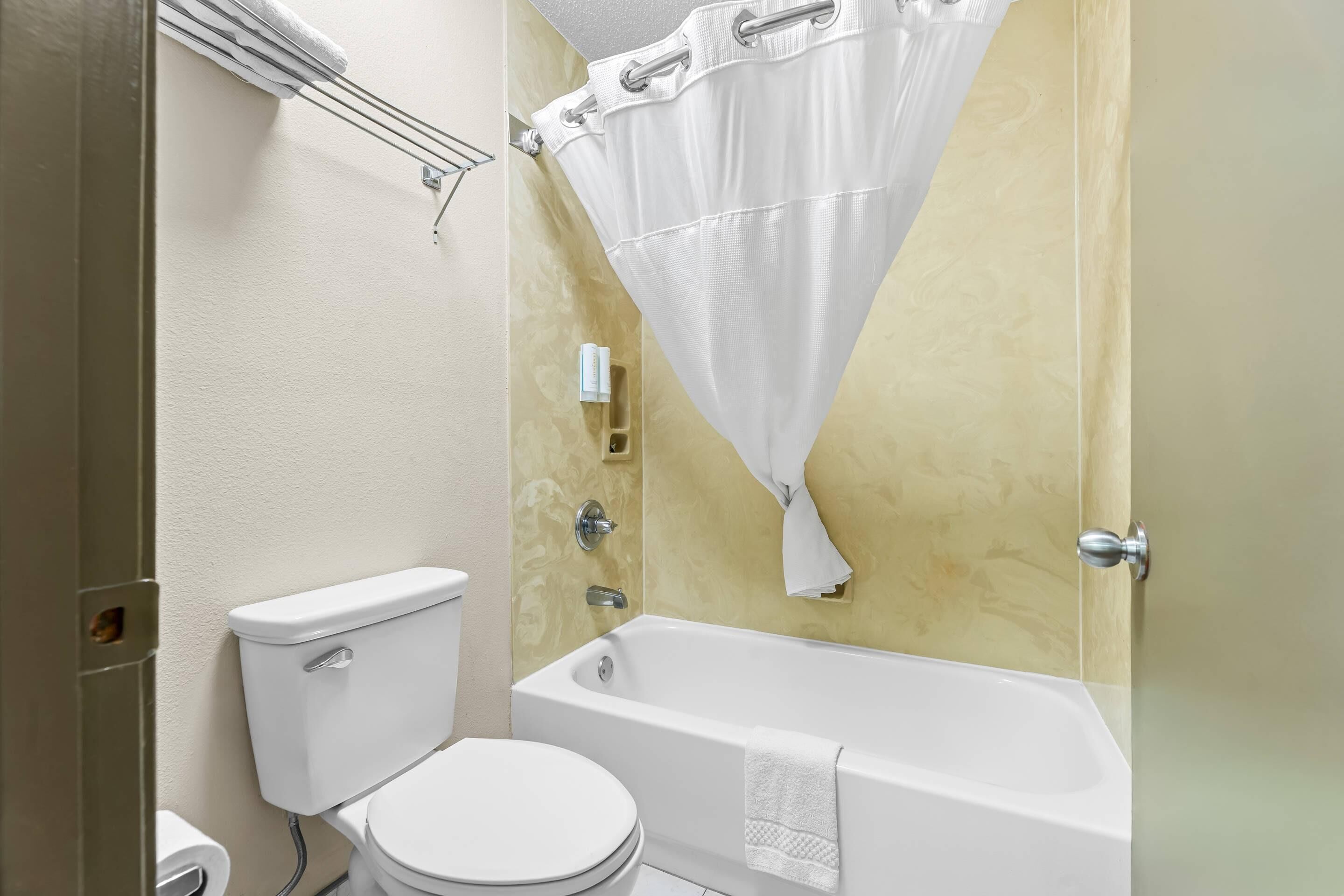 A bathroom with a toilet, bathtub, and shower curtain.