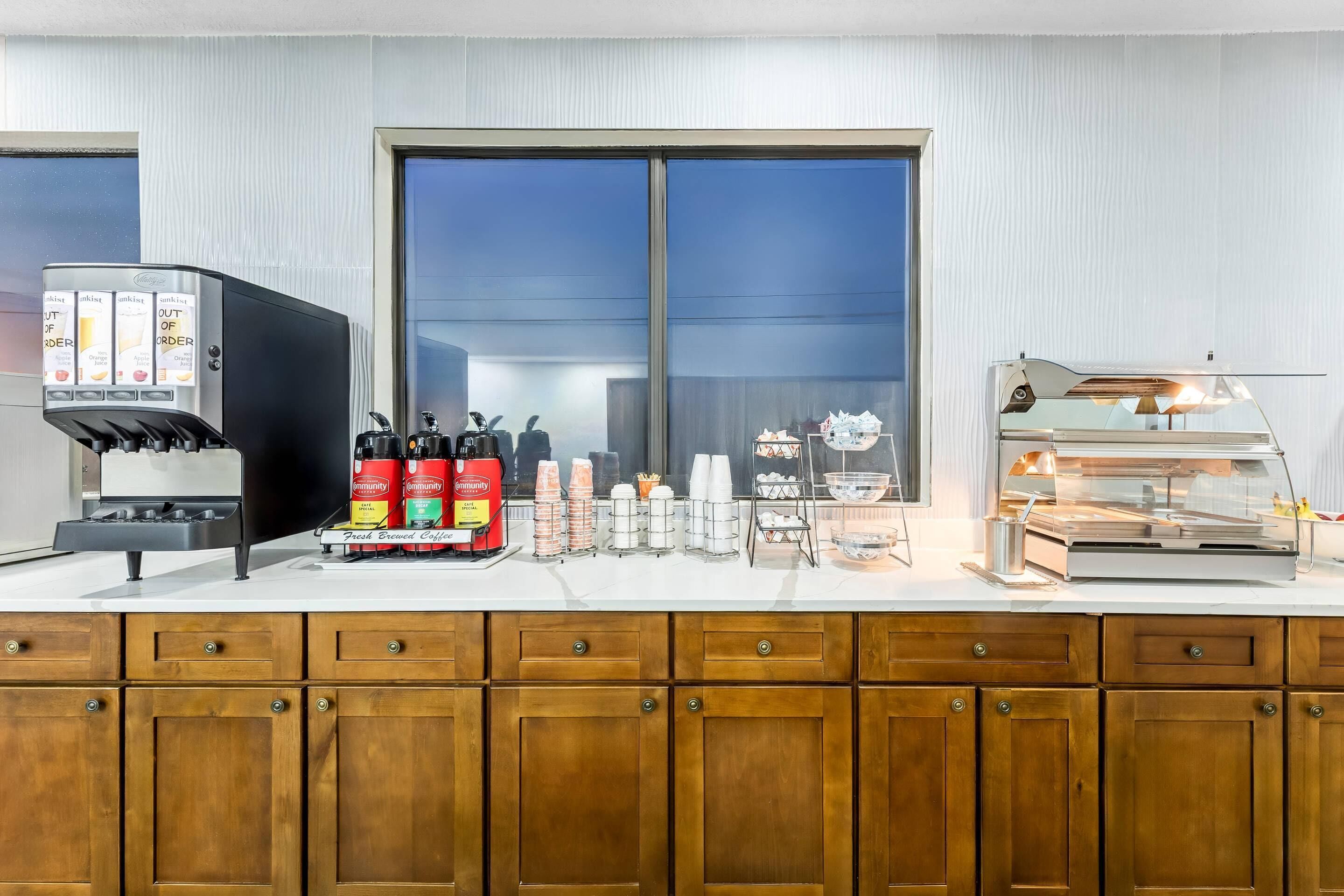 Eine Kaffeestation mit Kaffeeautomaten, Gewürzspendern und einer Vitrine mit Speisen.
