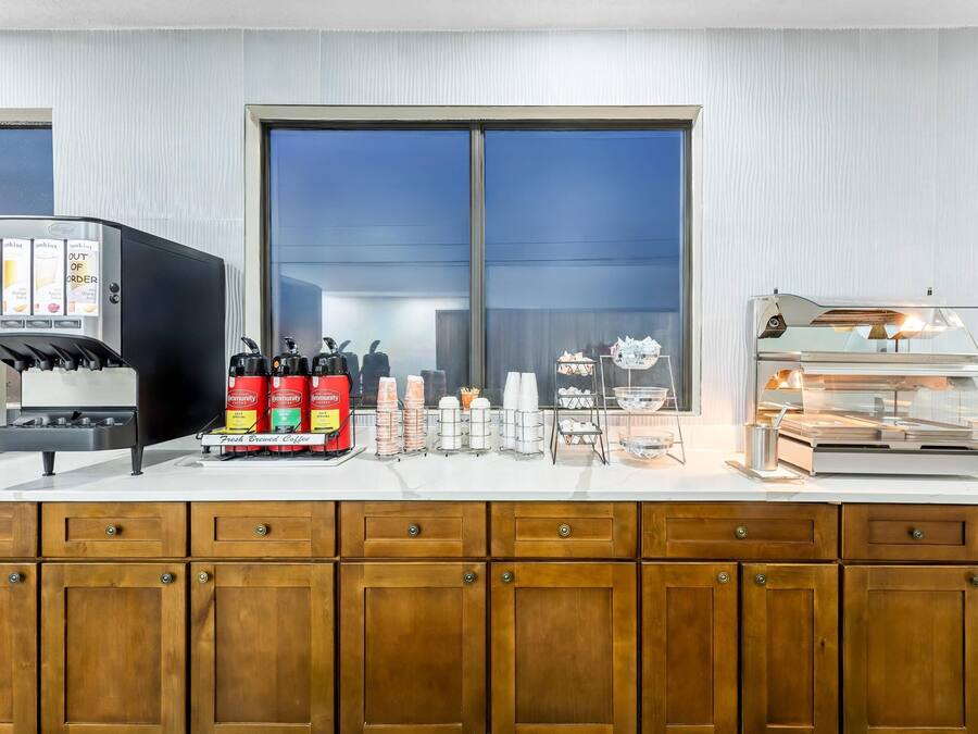 Eine Kaffeestation mit Kaffeeautomaten, Gewürzspendern und einer Vitrine mit Speisen.
