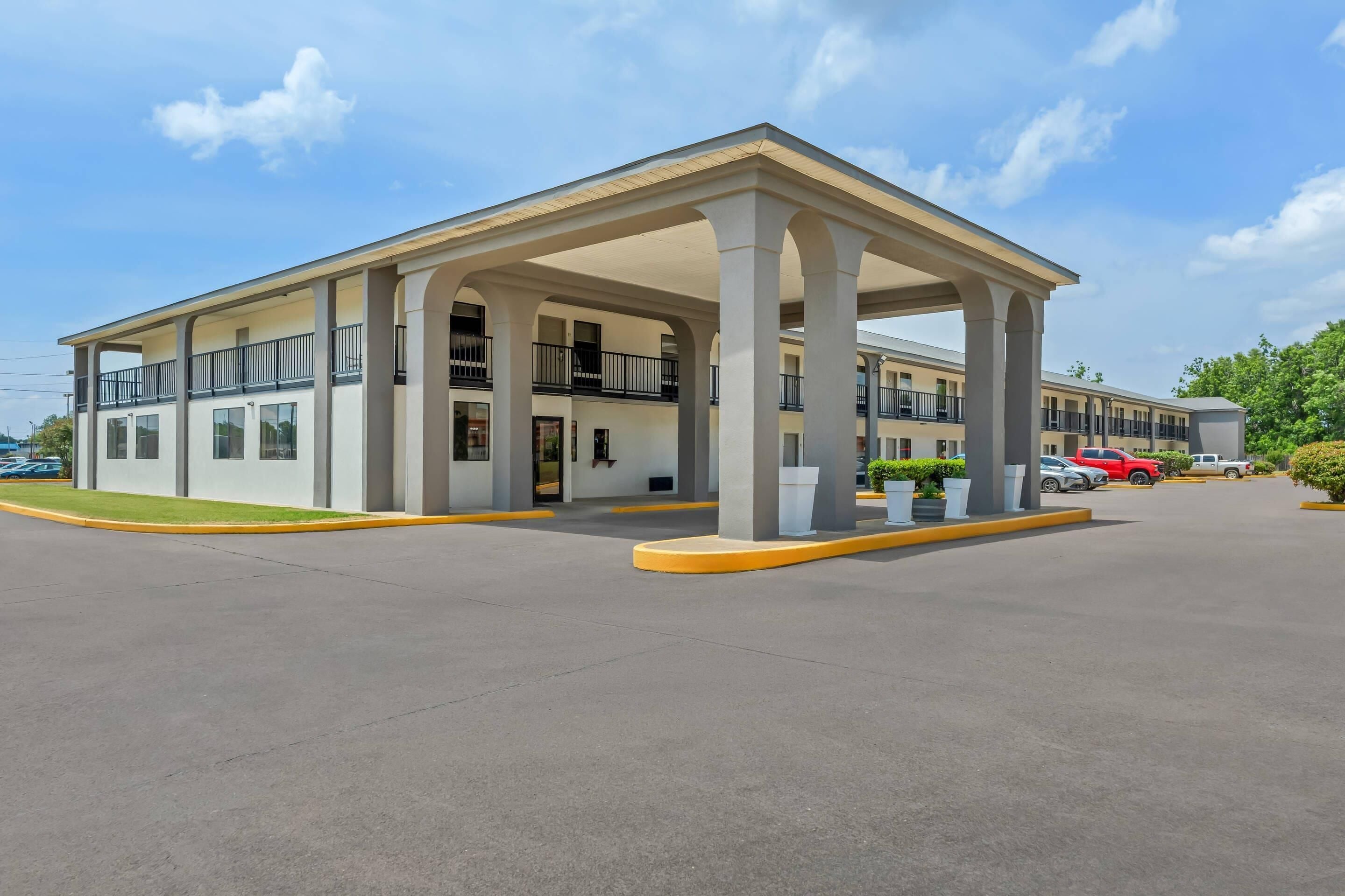 A multi-story hotel with a covered entrance, multiple balconies, and a parking lot.