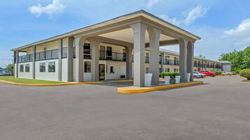 A multi-story hotel with a covered entrance, multiple balconies, and a parking lot.