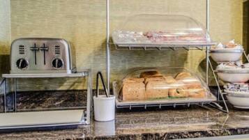 A kitchenette with a toaster, a bread display, and a bowl of food.