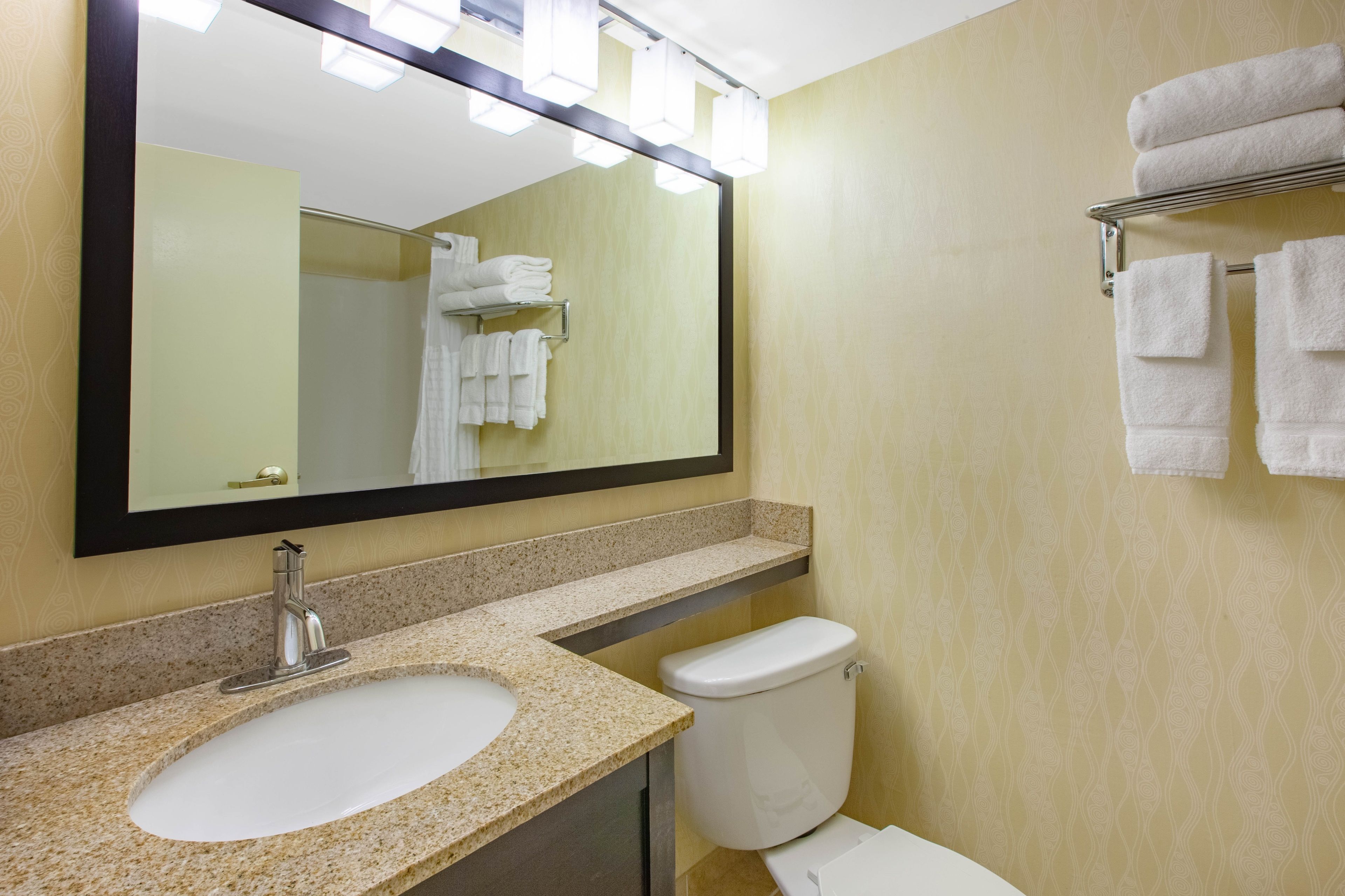 Un baño con lavabo, espejo e inodoro.