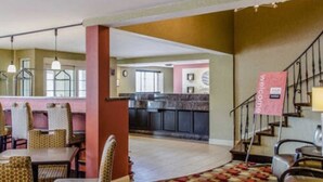 Un vestíbulo de hotel con comedor, una cocina al fondo y una escalera.