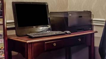 A wooden desk with a laptop, keyboard, mouse, and printer.