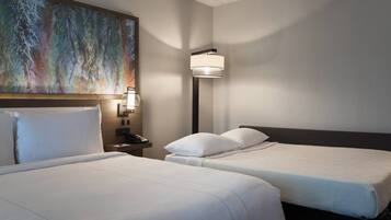 A hotel room with two beds, a nightstand, a lamp, and a large abstract painting on the wall.