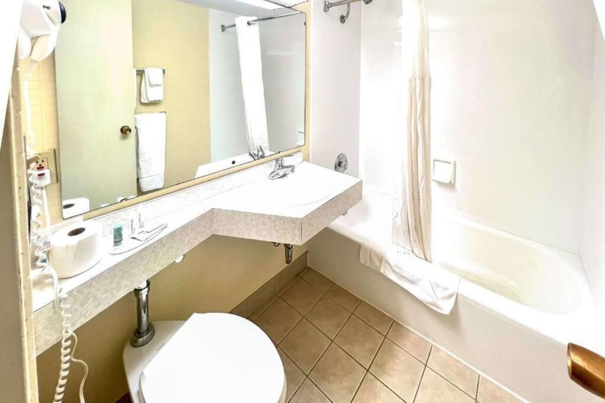 A bathroom with a sink, mirror, toilet, and bathtub.