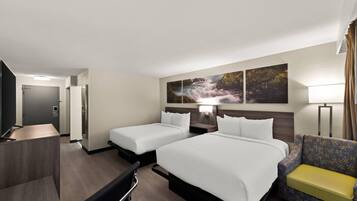 A hotel room with two beds, a desk, a chair, a sofa, and a painting of a waterfall on the wall.