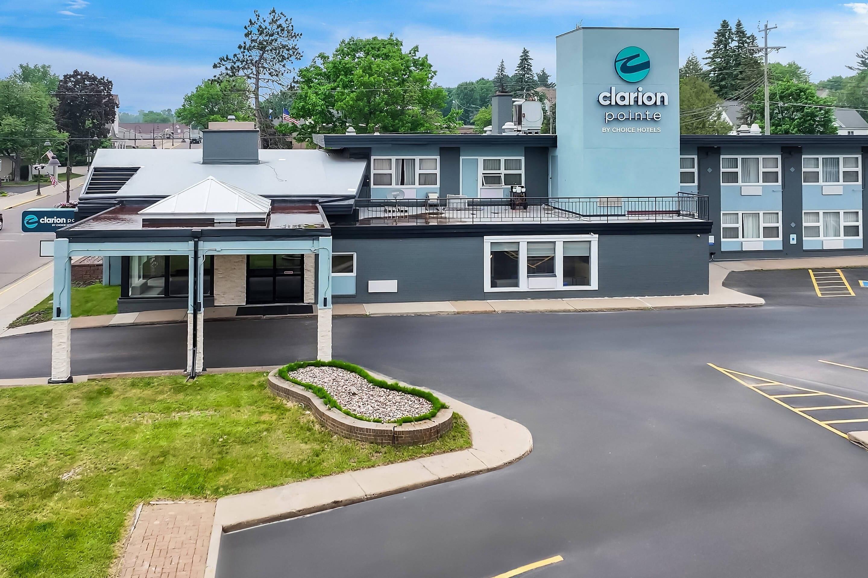 Un hôtel Clarion Pointe au design moderne, doté d’un espace extérieur couvert avec des sièges et d’un parking.