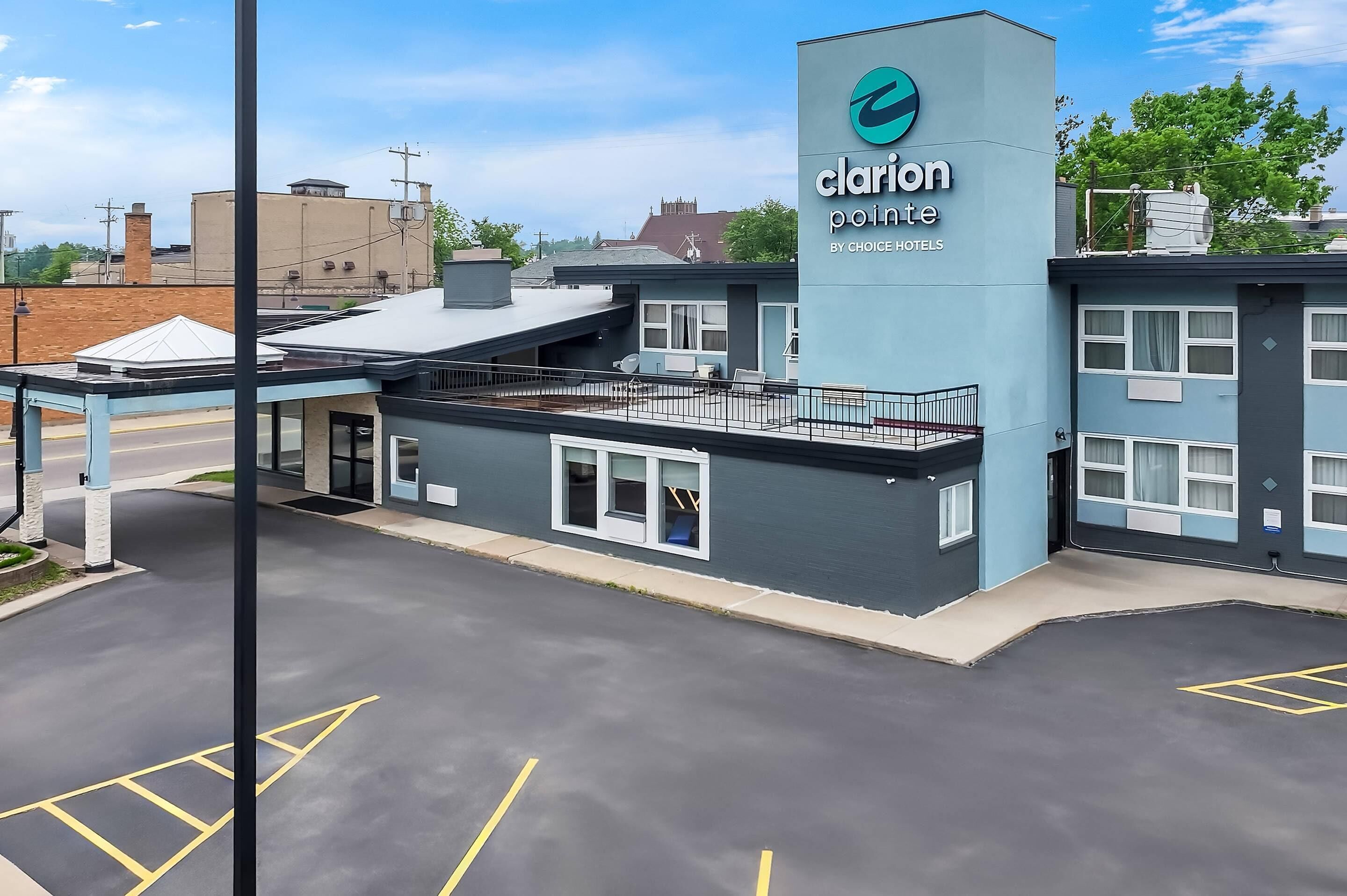 Un hôtel Clarion Pointe au design moderne, avec un logo bien visible, un espace extérieur abrité et un parking.