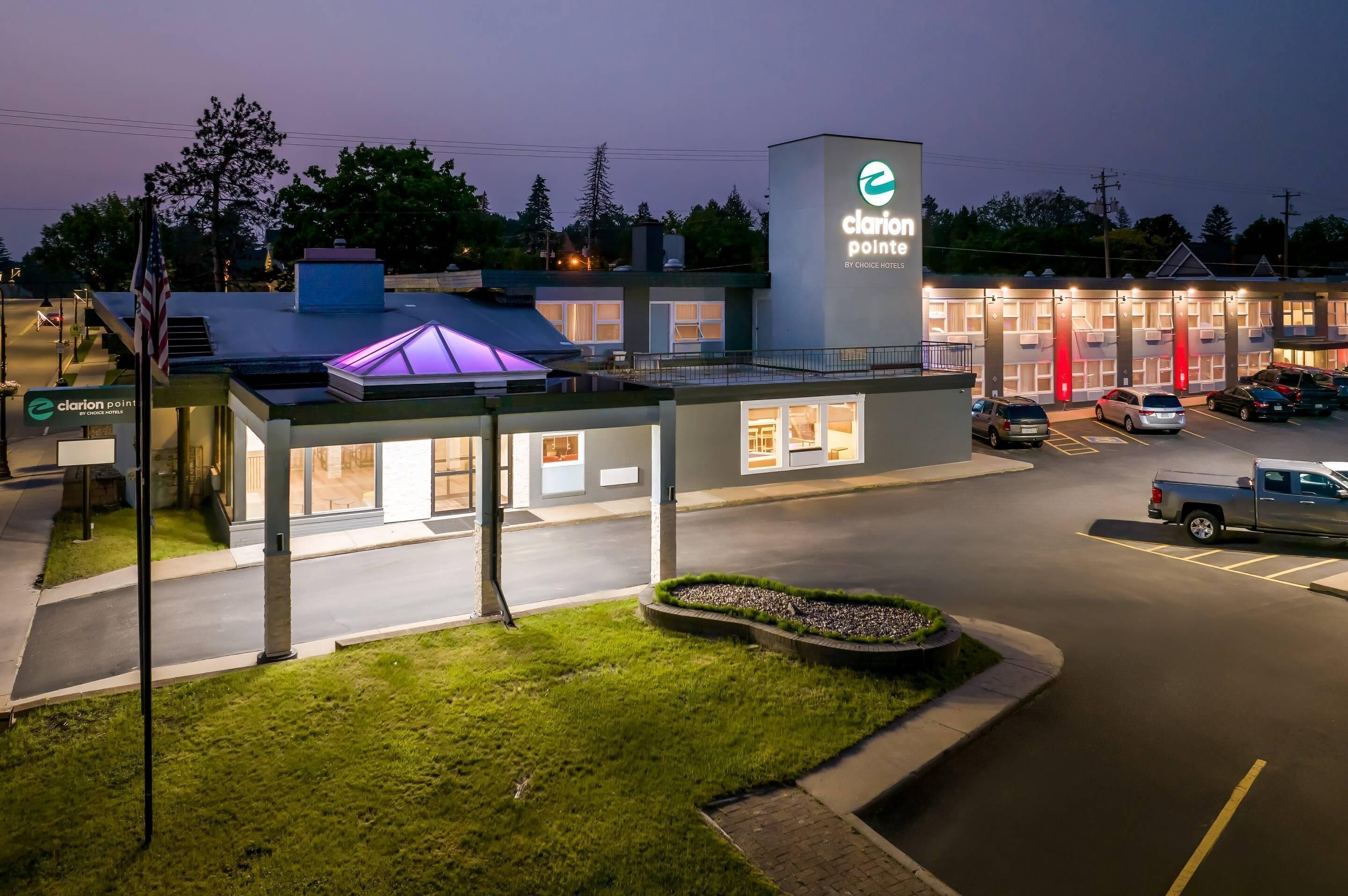 A Clarion Point hotel with a modern design, featuring a parking lot and a well-lit entrance.