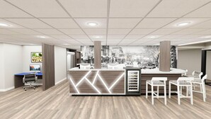 Un espace d’accueil comprenant un comptoir de réception en bois, un ordinateur et un coin bar avec des chaises blanches.