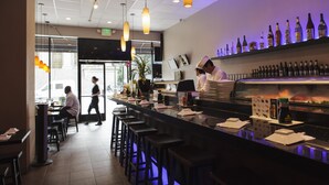 A bar area with stools, a counter, and shelves with bottles. - The Pickwick Hotel (San Francisco)