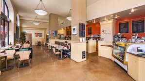 A spacious cafe with high ceilings, pendant lighting, and a variety of seating options including tables and benches. - The Pickwick Hotel (San Francisco)