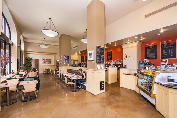 A spacious cafe with high ceilings, pendant lighting, and a variety of seating options including tables and benches.