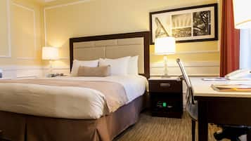 Una habitación de hotel con una cama grande, mesitas de noche, un escritorio y una lámpara.