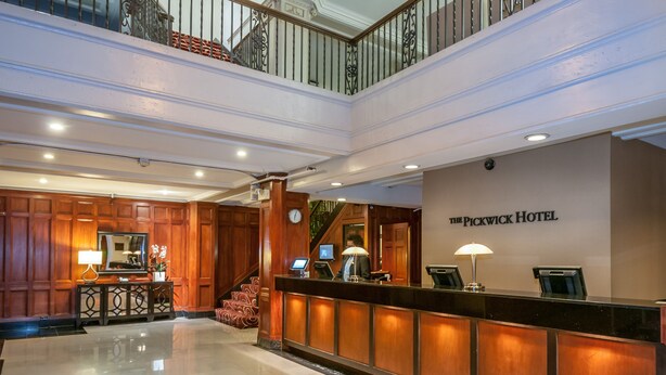 A hotel reception area with a polished marble floor, wooden paneling, and a reception desk with a computer and a telephone. - The Pickwick Hotel (San Francisco)