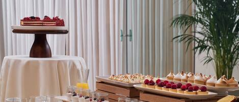 Una mesa de buffet con diversos postres y pasteles, incluyendo un pastel con frutos rojos, dispuesta sobre pedestales y platos de madera.