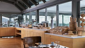 A modern kitchen with wooden cabinets, a dining area with a table set for two, and a large window with a view of the city.