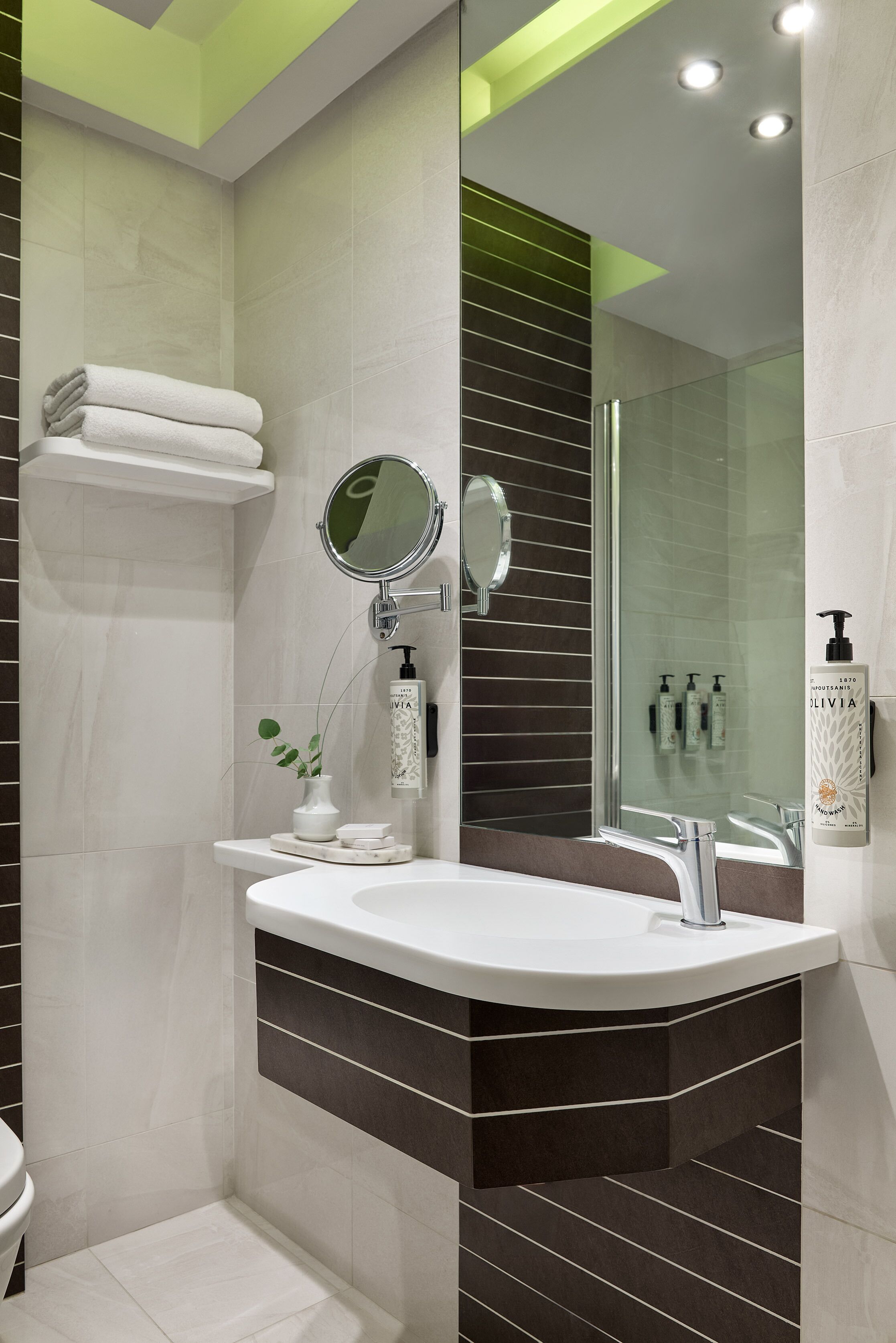 A modern bathroom with a curved sink, a glass shower enclosure, and a mirror above the sink.
