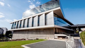 Un edificio moderno con fachada de vidrio, amplias ventanas y techo plano.