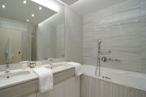 Un baño moderno con dos lavamanos, un espejo grande y una bañera.