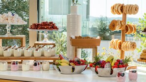 Un bufé con diversas opciones de comida, incluyendo frutas, pastelería y postres.