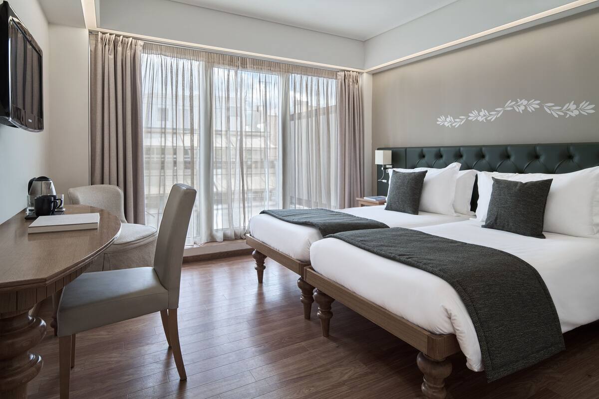 Una habitación de hotel con cama, mesita de noche, silla y escritorio con otra silla.