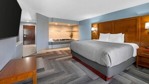 A hotel room with a large bed, a wooden headboard, a bedside table, and a small bedside lamp. - Quality Inn & Suites Goshen (Goshen)