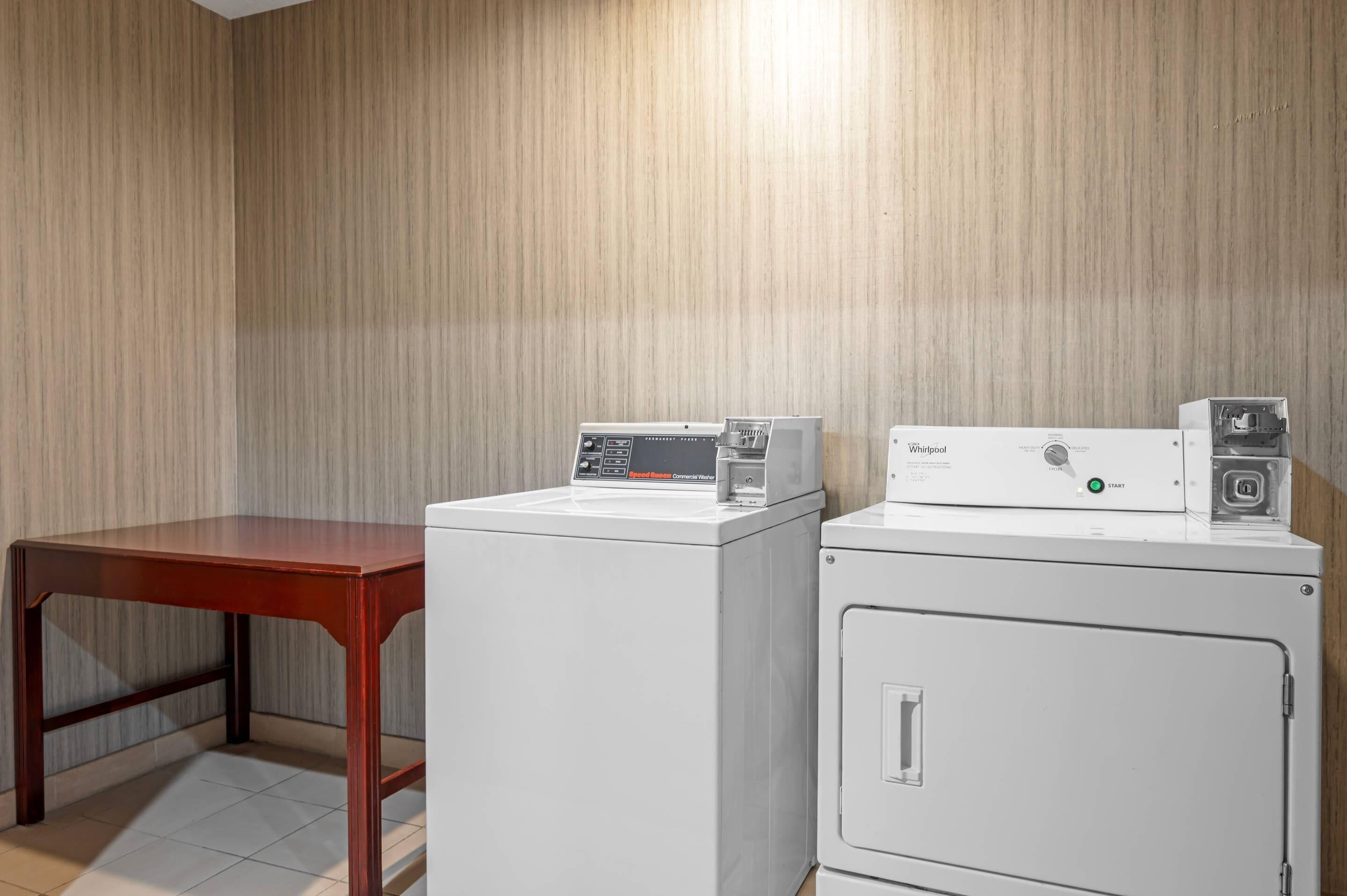 A laundry area with a wooden table and two white washing machines.