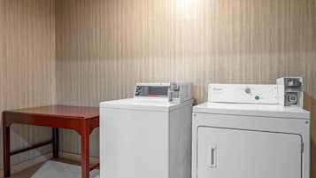 A laundry area with a wooden table and two white washing machines.