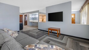 A living room with a sofa, a television, a small wooden table, and a patterned rug. - Quality Inn & Suites Goshen (Goshen)