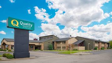 Un hôtel affichant une enseigne indiquant « Quality Inn & Suites by Choice Hotels », avec un bâtiment moderne doté d’un toit plat et d’un parking.