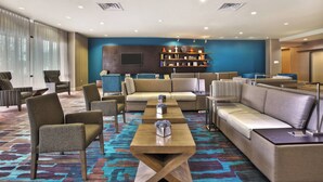Un vestíbulo de hotel con disposiciones para sentarse, una mesa de centro y una estantería.