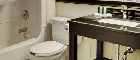 A bathroom with a bathtub, toilet, sink, and a mirror.
