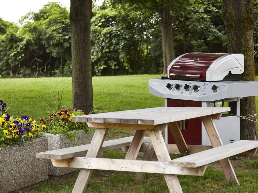 A picnic table with a barbecue grill in a park.