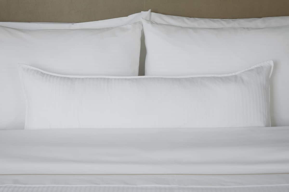 Un lit bien fait, avec du linge de lit blanc et des oreillers.