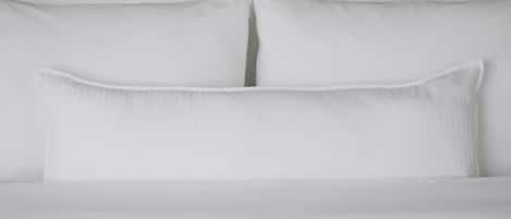 A neatly made bed with white linens and pillows.