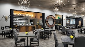 Un restaurante con zona de bar, varias mesas y sillas, y lámparas decorativas.
