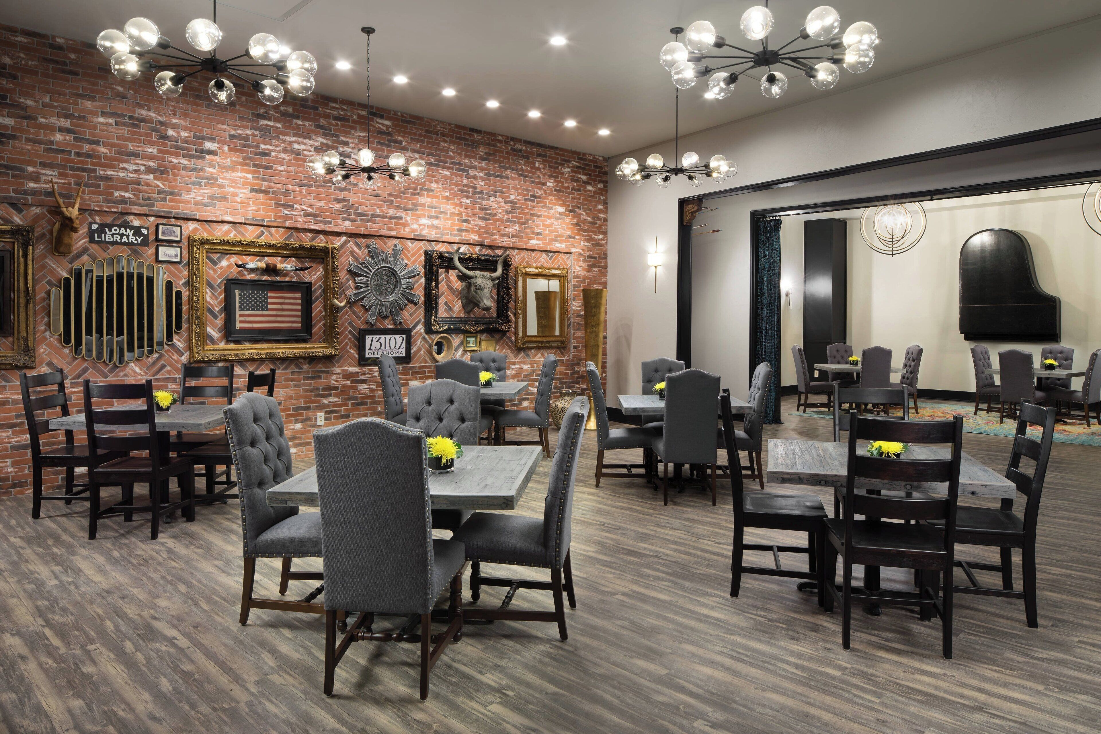 A dining area with brick walls, multiple tables and chairs, and decorative wall art.