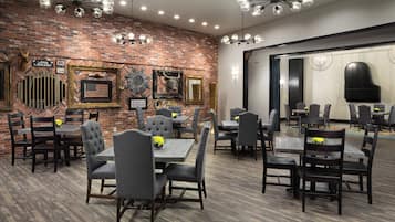 A dining area with brick walls, multiple tables and chairs, and decorative wall art.