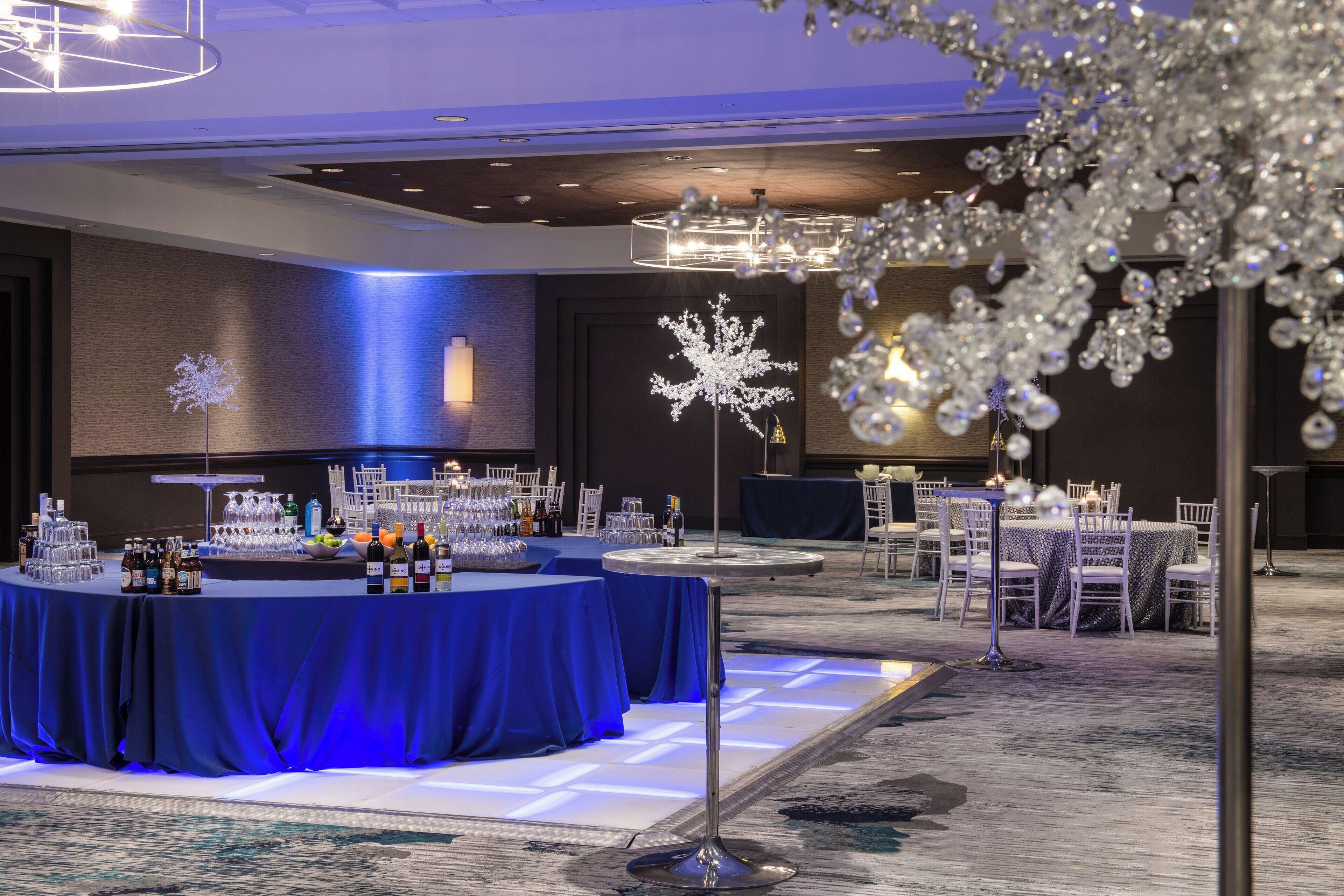 Une salle de banquet avec une table ronde recouverte d’une nappe bleue, entourée de chaises blanches.