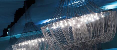 A modern interior with a large, illuminated, geometric chandelier.