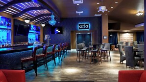 Zona de bar con mostrador, taburetes y un letrero de neón que dice "aria".