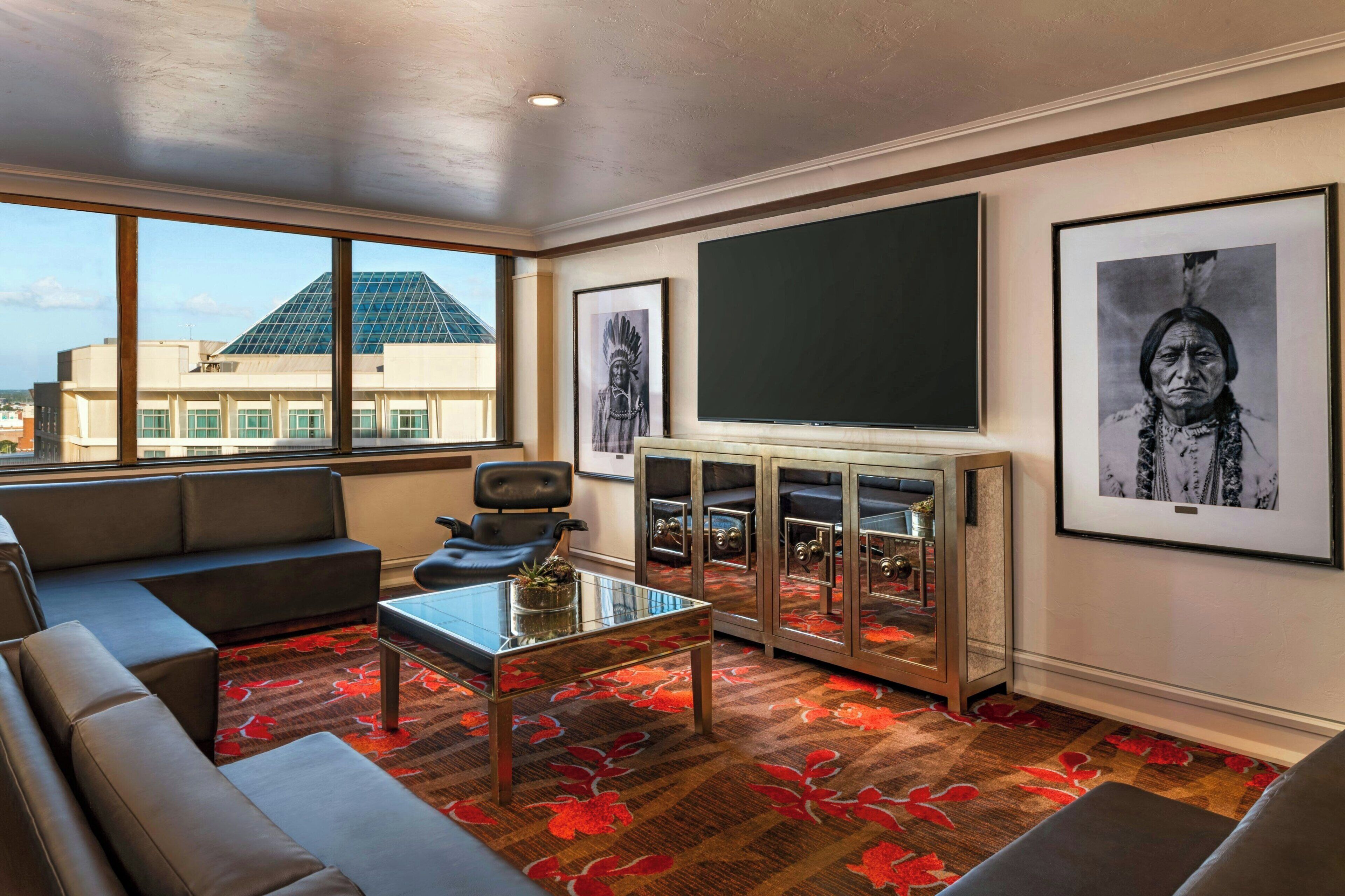 A modern room with a sofa, a glass coffee table, a television, and framed pictures on the wall.
