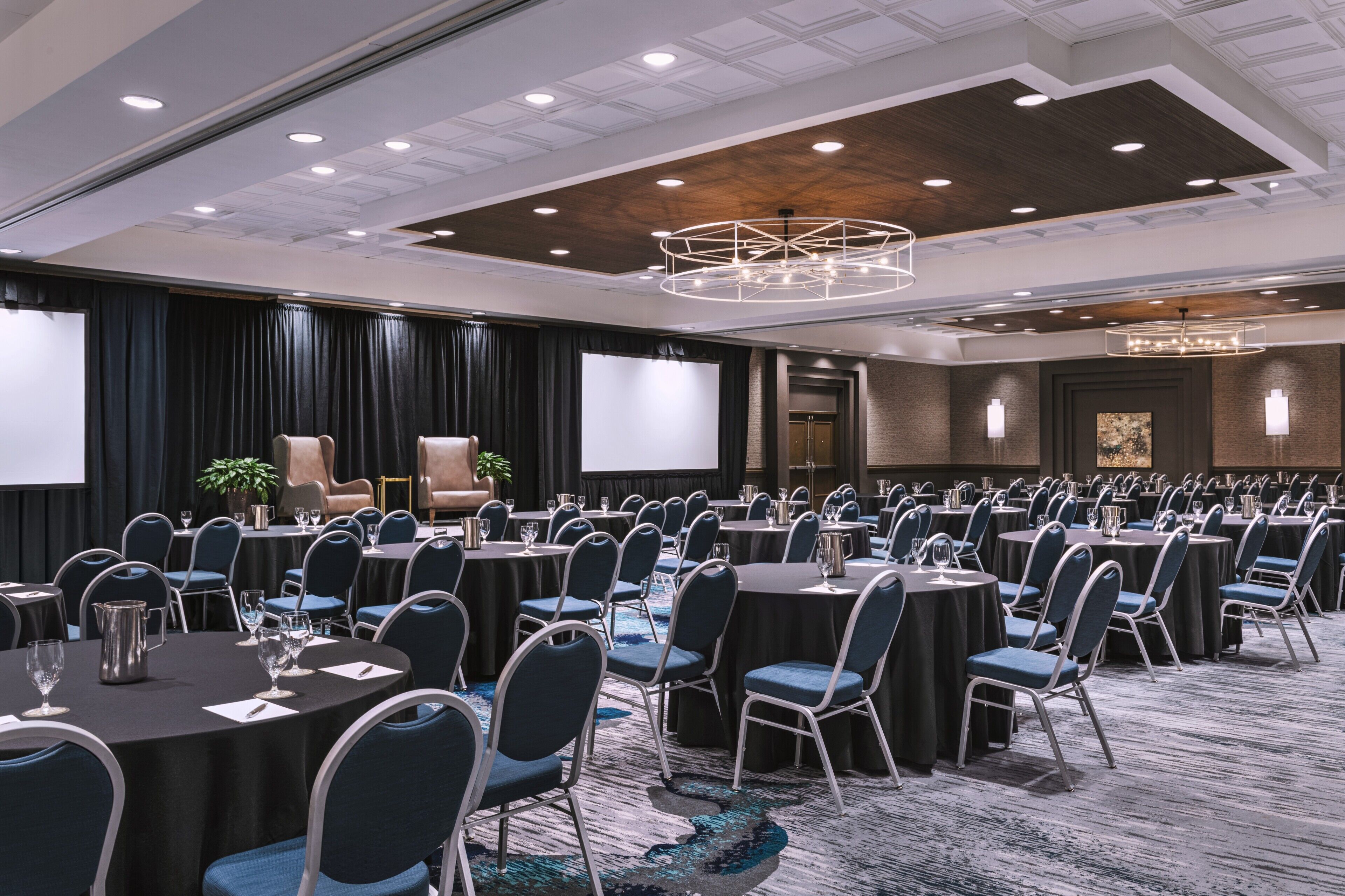 A conference room with round tables, chairs, and a large screen.